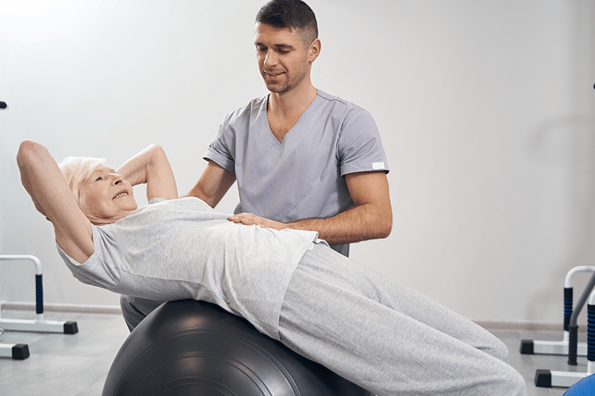 Senior female lying on exercise ball during back stretching