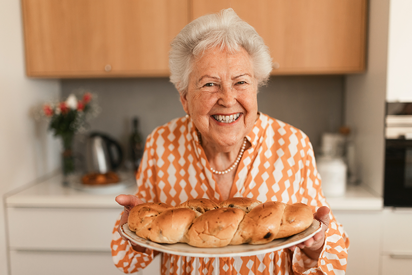 Happy senior woman holding homemade sweet braided bread