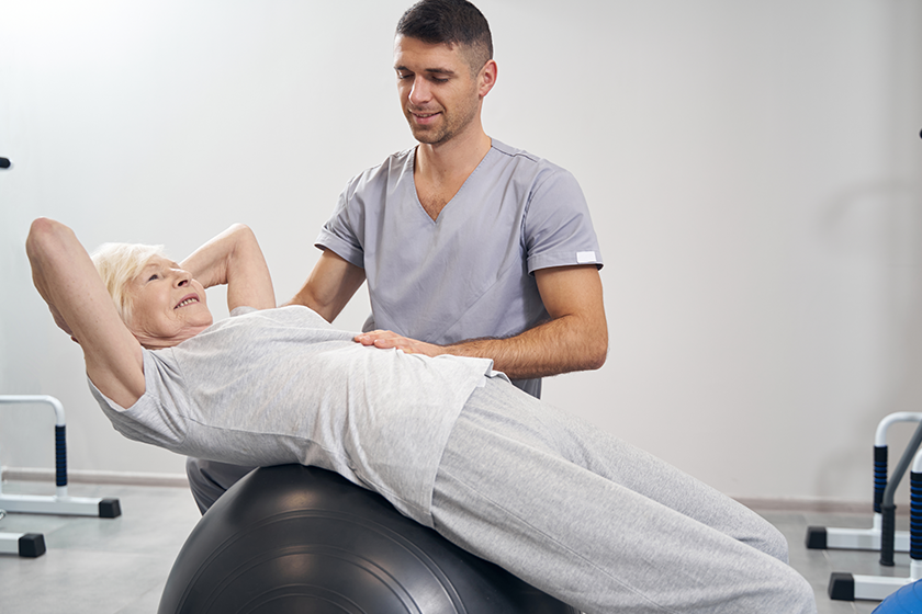 Senior female lying on exercise ball during back stretching